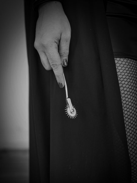 Mysteriöse Fetisch-Ästhetik: Hand mit Wartenberg-Rad in Netzstrümpfen & schwarzem Outfit